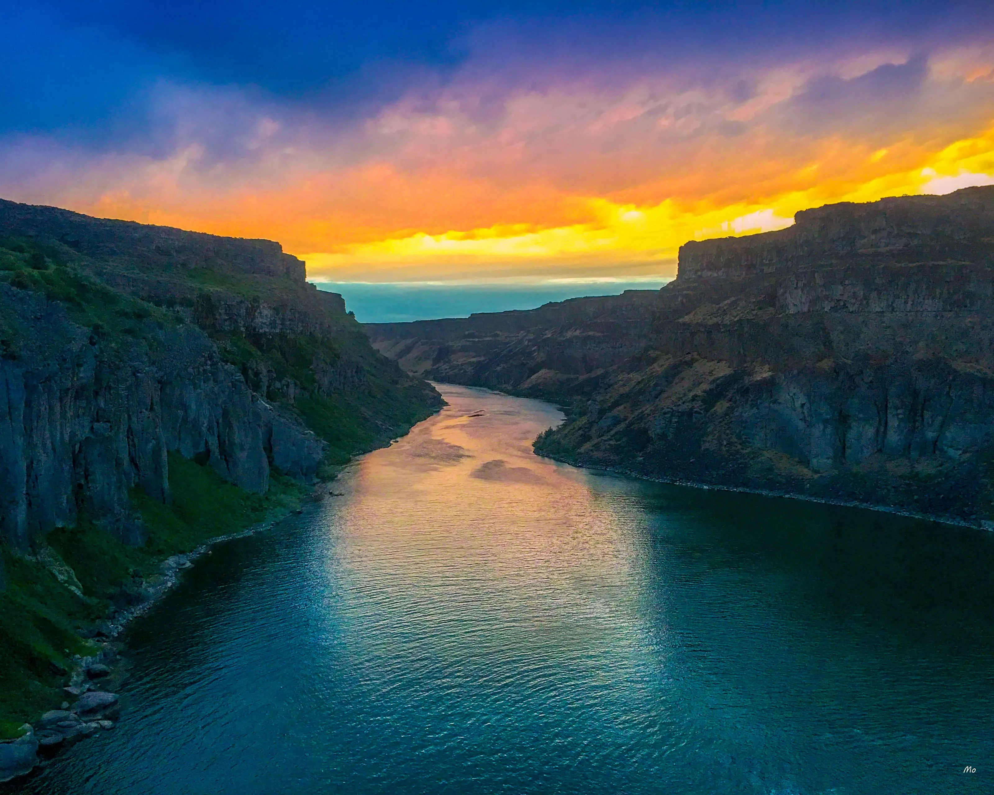 A river winding through a deep canyon toward a bright sunset